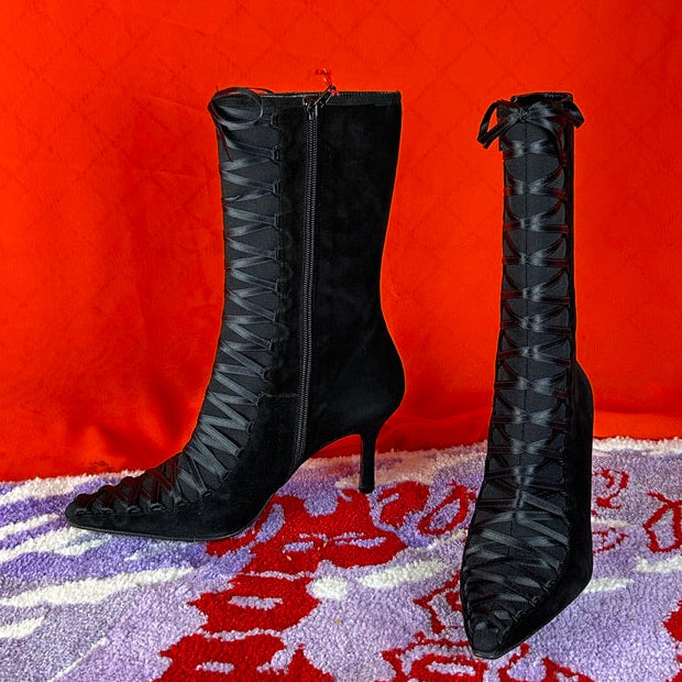 Black high-heeled boots on a patterned surface with an orange background
