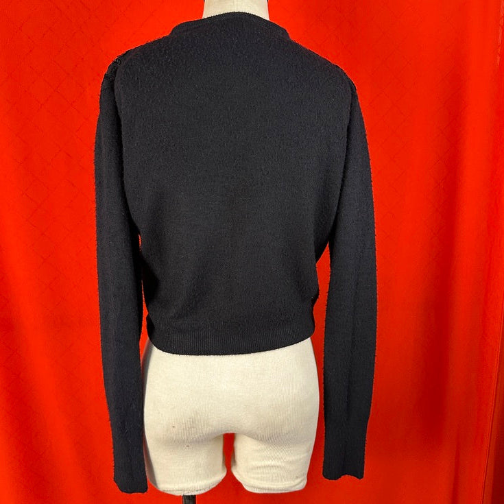 Black sweater on a mannequin against a red background