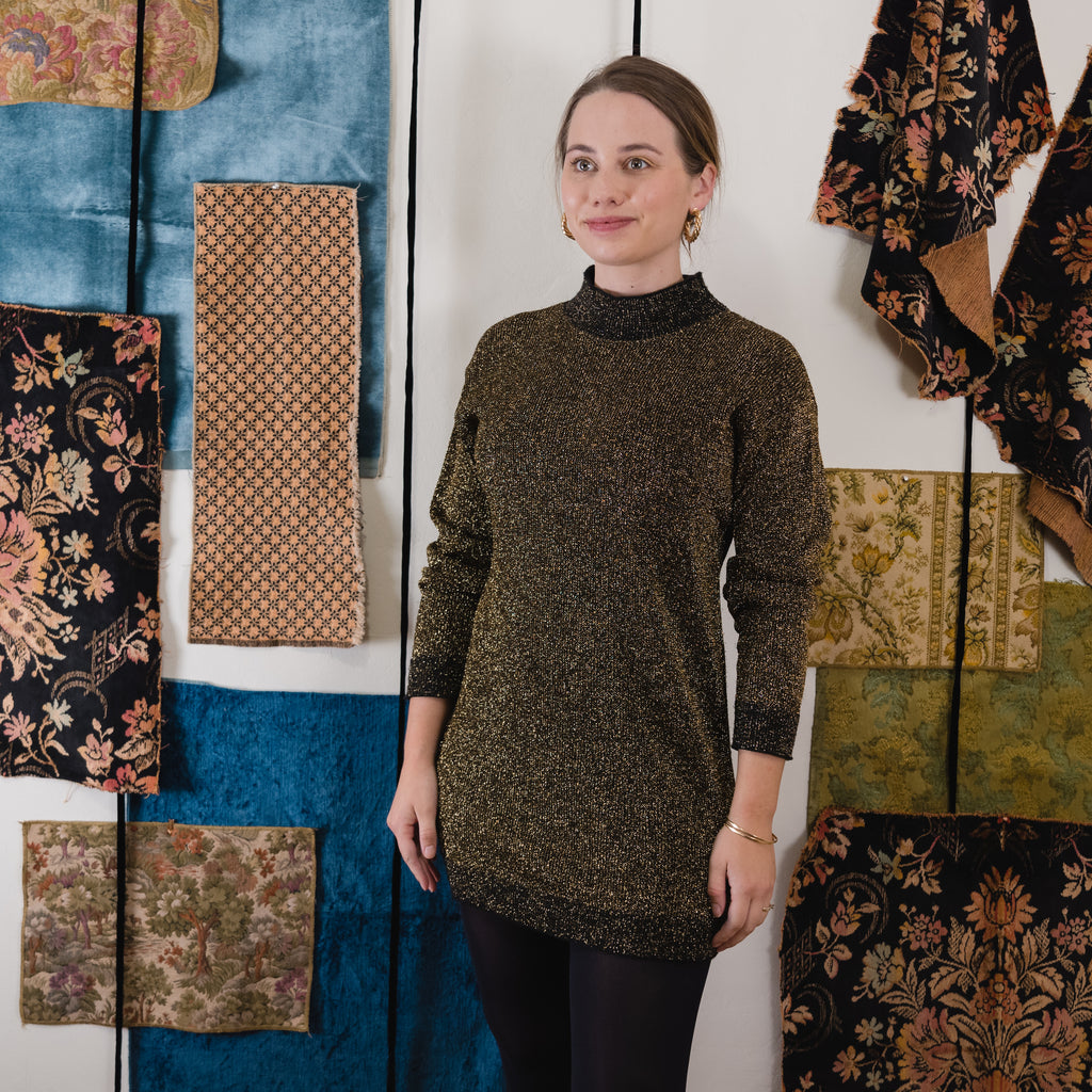 young lady wearing a Pierre Cardin knit tunic or dress in front of a wall with various hanging fabrics